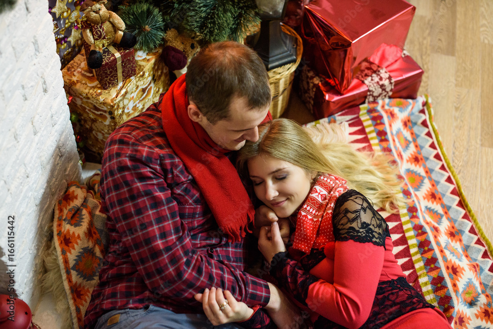 Young couple cuddling and kissing near christmas tree. Merry Christmas and Happy New Year!