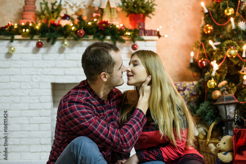 Happy couple with christmas gifts relaxing and kissing at home. Merry Christmas and Happy New Year!