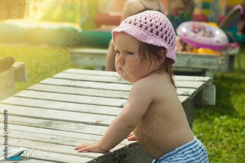 Little baby girl near the sunbeds by the aquapark in the sunny day, toned photo photo