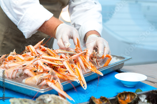 Close up of hands of chef preparing a dishs with hrimps  photo