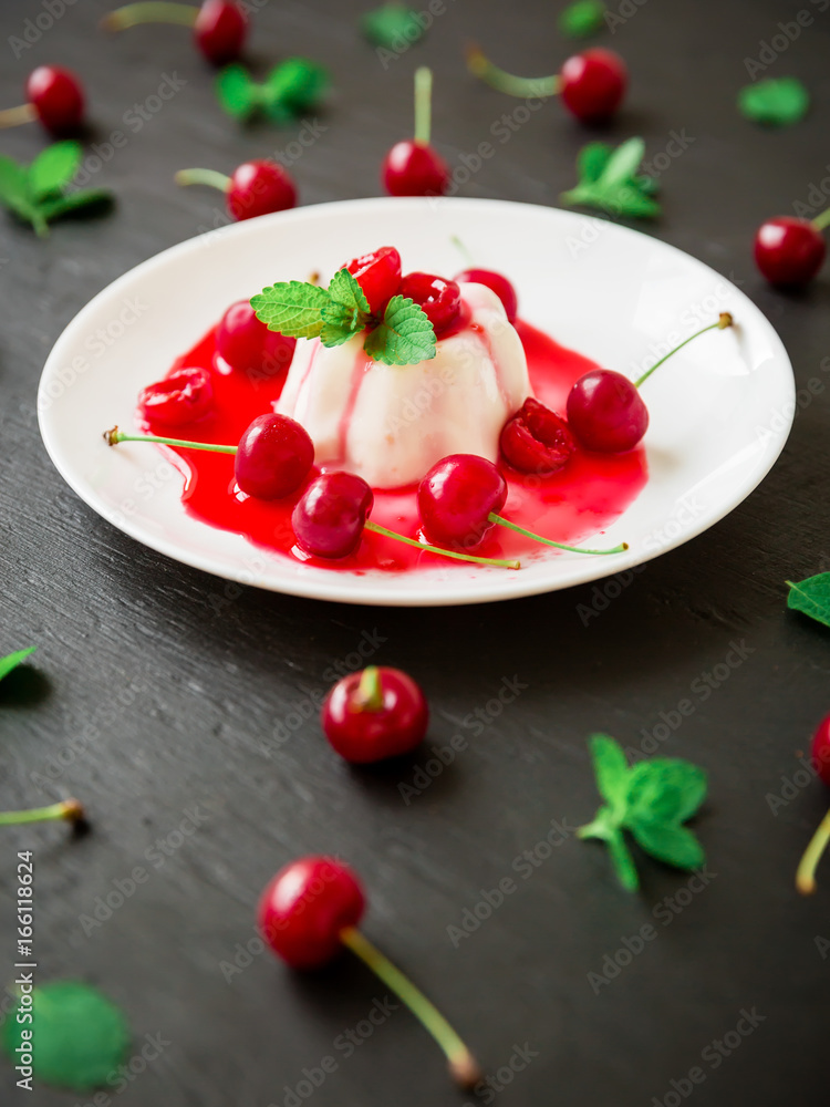 Tasty Italian jelly with cherry berries in white plate on dark table Tasty Italian jelly with cherry berries in white plate on dark table