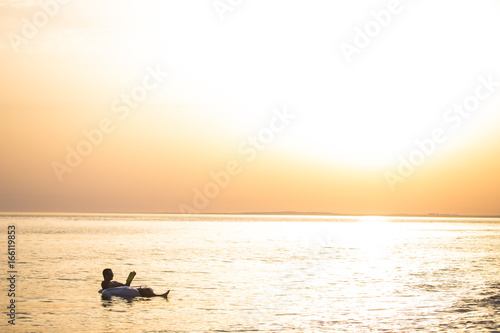 Caucasian man reads a book floating on the sunset in the ocean water. Summer vocation. © F8  \ Suport Ukraine