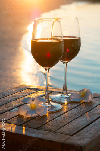 Romantic outdoor scene: two glasses of red wine at sea sunset