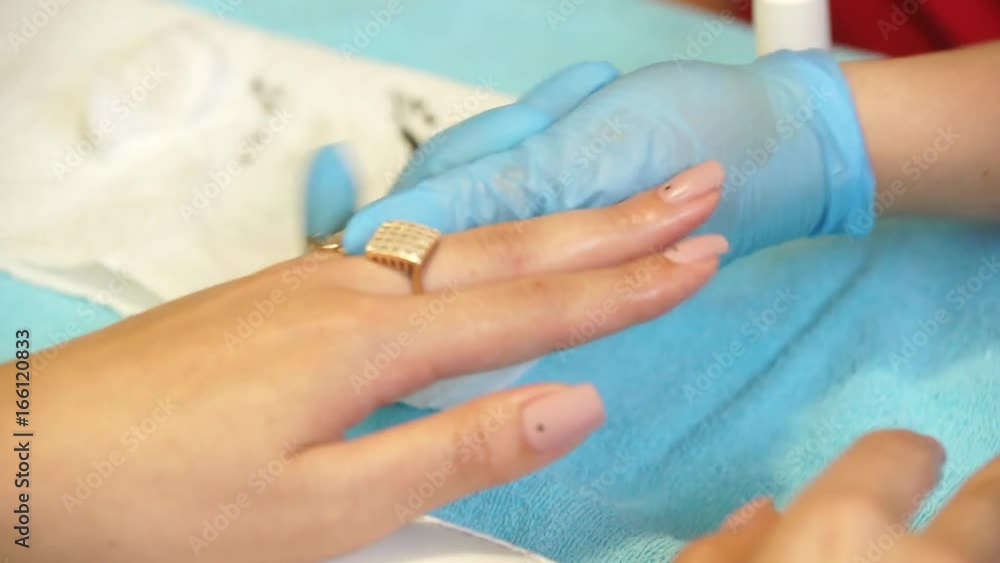Manicure salon procedures The manicure master does the manicure to the client. She paints her nails with a brush covered with gel-lacquer Manicure salon procedures The manicure master does the manicure to the client. She paints her nails with a brush covered with gel-lacquer