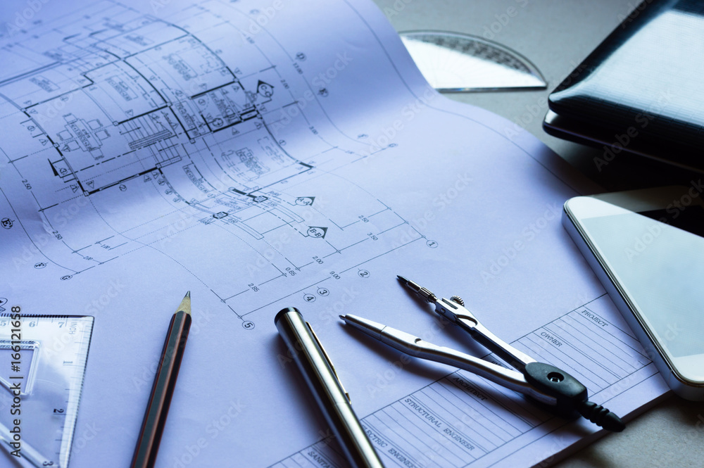 Divider, pencil, pen, ruler, glasses and smartphone and blueprint on table top.Table top view of Engineers table at office workplace.selective focus. Divider, pencil, pen, ruler, glasses and smartphone and blueprint on table top.Table top view of Engineers table at office workplace.selective focus.