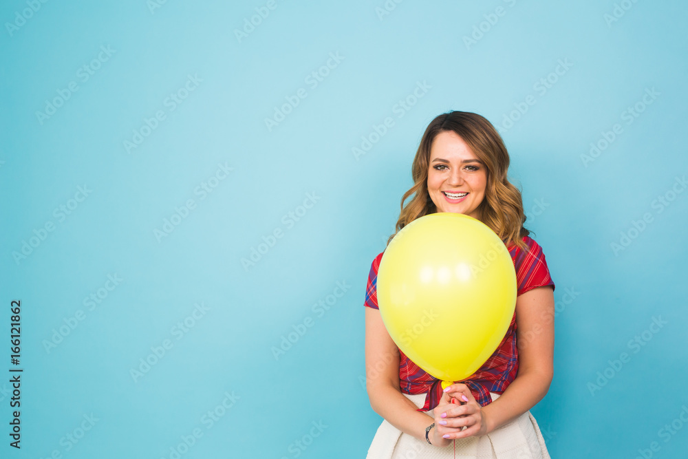 Fashion smiling young woman with yellow air balloon over colorful blue background with copyspace. Fashion smiling young woman with yellow air balloon over colorful blue background with copyspace.