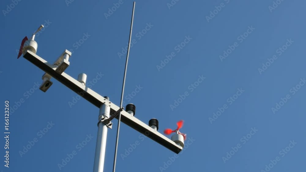 The anemometer in the sun's rays measures the wind speed. The meteo station on the blue sky background. The anemometer in the sun's rays measures the wind speed. The meteo station on the blue sky background.