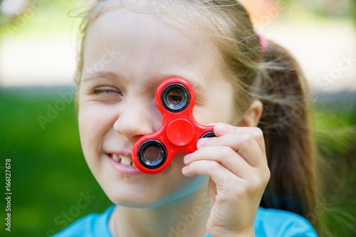 little girl holding a red fidget spinner outdoors