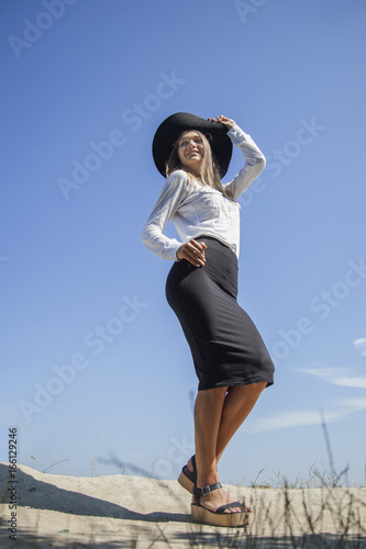 Portrait of beautiful young happy woman on holiday against blue background of sky. (Vacation, summer, sea concept)