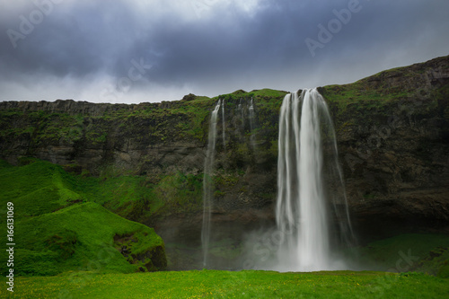 Iceland - Waterfall of Seljalandsfoss with green meadow
