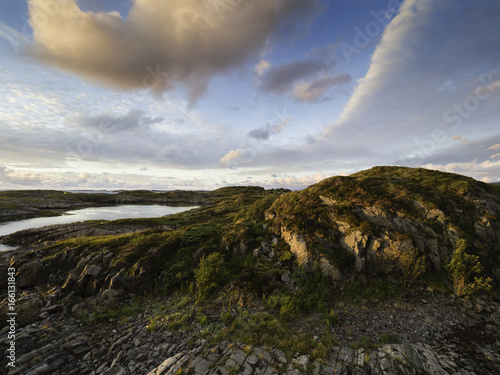 Beautiful sunset rocky landscape with the yellow blue cloudy sky on the Atlantic road, Norway. photo