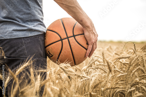 a young man with a basketball on the nature, concept of sport © puhimec