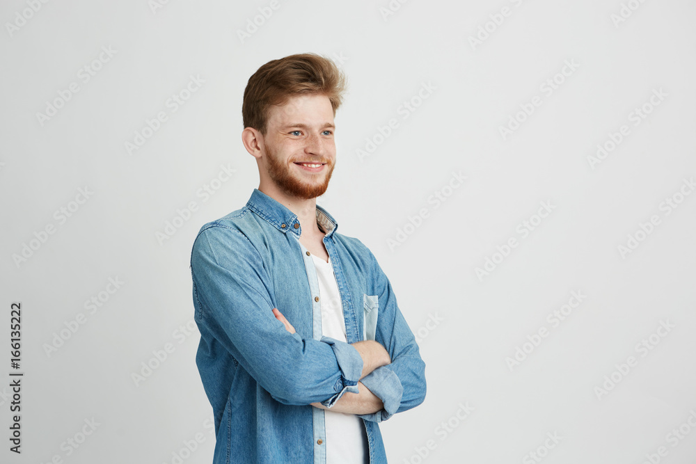 Portrait of cheerful confident young handsome man with beard smiling over white background. Crossed arms. Portrait of cheerful confident young handsome man with beard smiling over white background. Crossed arms.