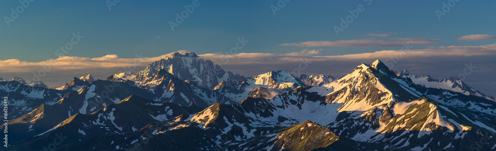 First rays of raising sun on mountain peak. Mounts Zakzan-Syrt and Pshish. Caucasus Mountains.