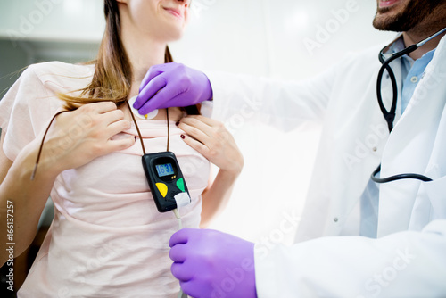 Young smiling woman wearing a holter heart monitor. photo