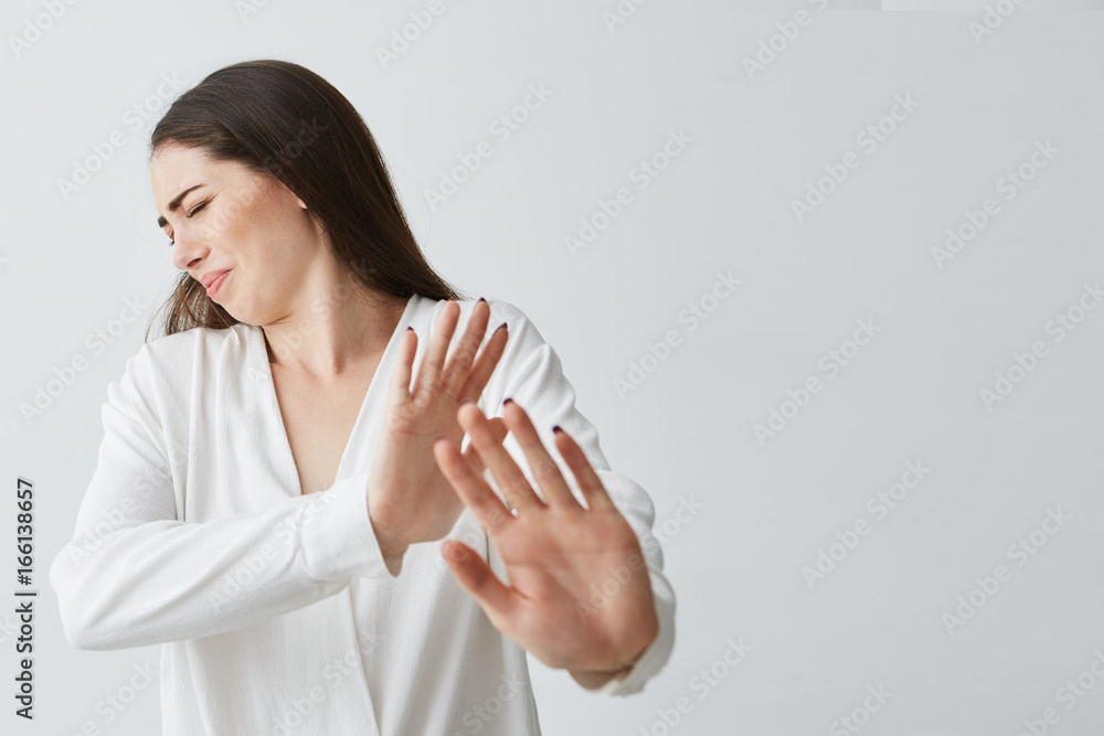 Displeased young beautiful woman showing stop stretching from camera over white background. Displeased young beautiful woman showing stop stretching from camera over white background.