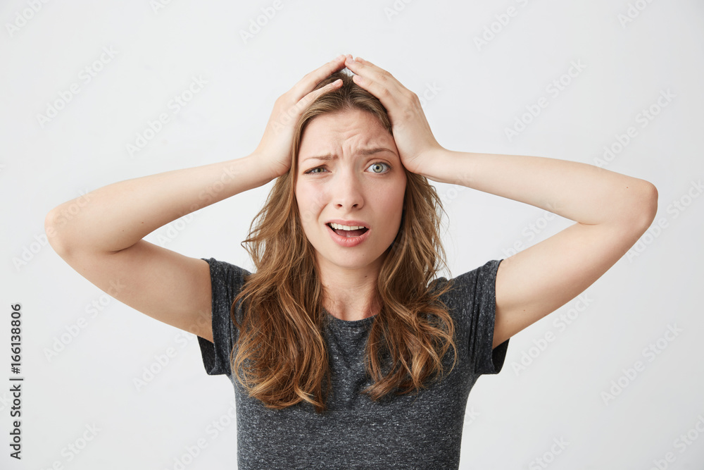 Embarrassed young pretty girl holding her head looking at camera over white background. Embarrassed young pretty girl holding her head looking at camera over white background.