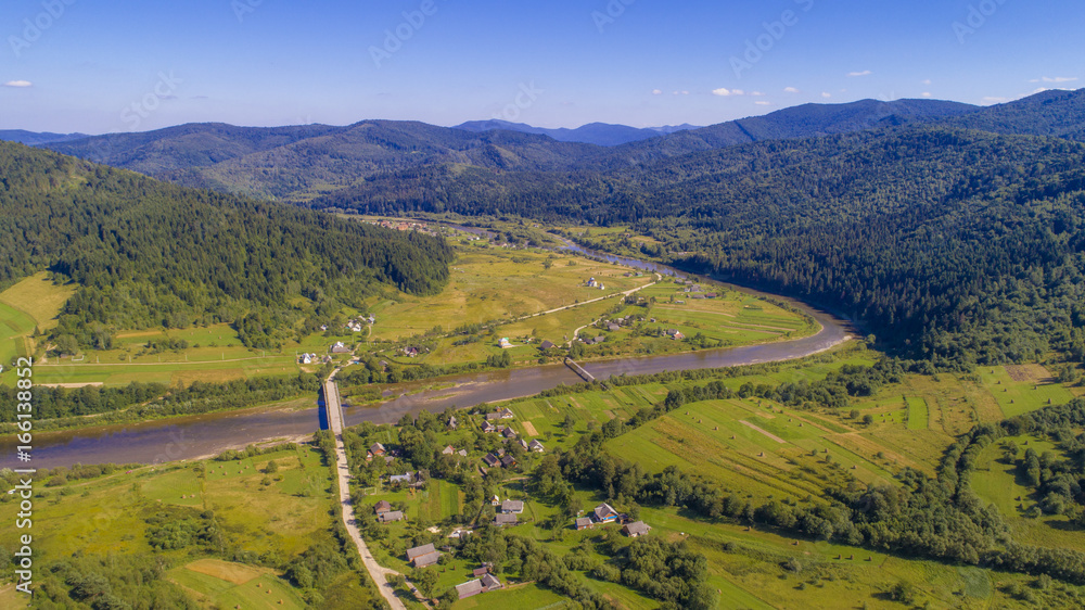  a beautiful summer landscape shot from a bird's eye view. mountains, river, green fields and villages.