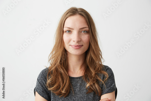 Portrait of young pretty positive girl smiling looking at camera over white background.