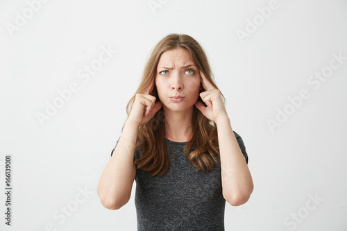 Young beautiful girl thinking with fingers on temples looking up over white background.