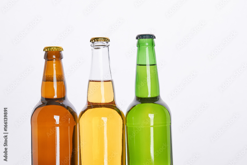 Three bottles with beer close up. Set of alcoholic liquid, white background. Three bottles with beer close up. Set of alcoholic liquid, white background.