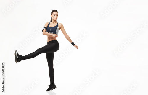 Fitness sport attractive girl in headphones warming up training over white background.