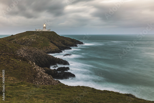 Moody seascape with lighthouse on the cliffs