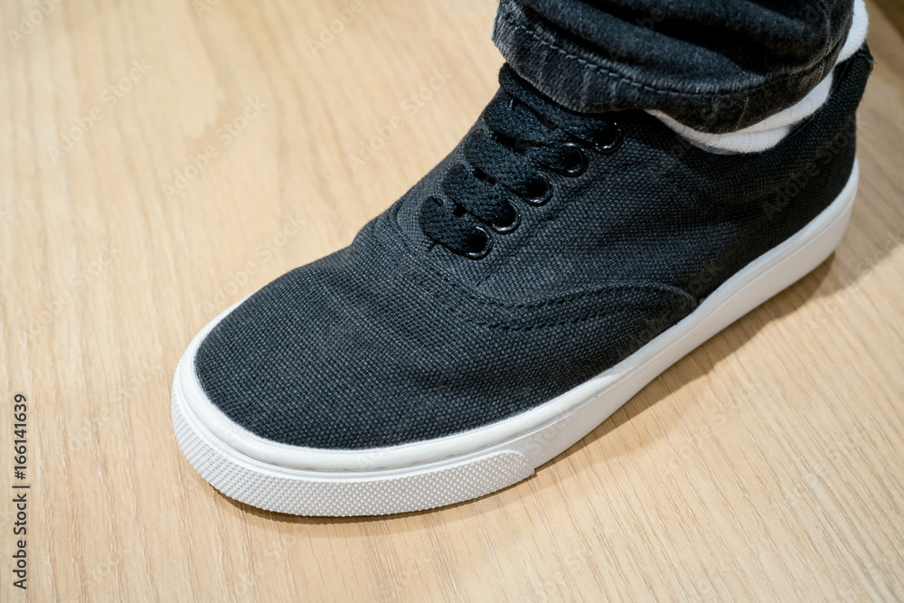 Black canvas sneaker under dark boot cut jeans