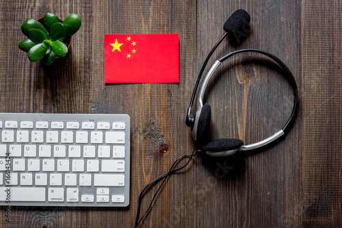 Self-development. Learning chinese online. Headphones and keyboard on wooden table background top view