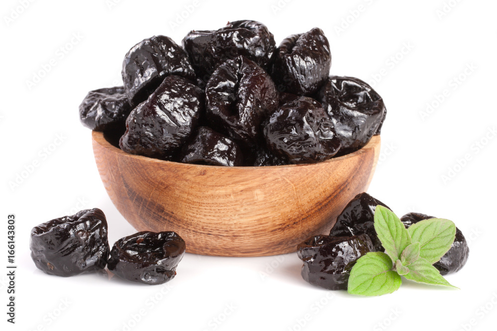 Dried plums or prunes with a mint leaf in wooden bowl isolated on white background Dried plums or prunes with a mint leaf in wooden bowl isolated on white background