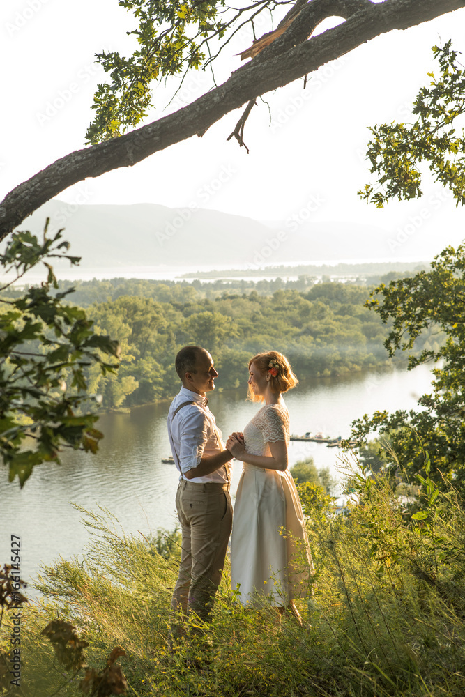 Fototapeta premium Attractive couple enjoying romantic sunset on the top of the hill.