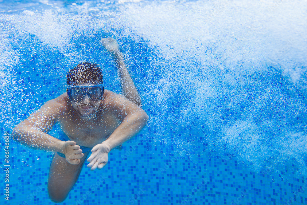 Naklejka premium Young man in diving mask swimming the front crawl in a pool, taken under water