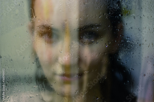 Beautiful woman behind the glass with water drops looking directly at camera. Girl takes a shower, voyeurism © Руслан Галиуллин