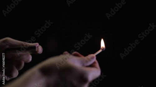 A match being lit and put out in front of a solid black background.