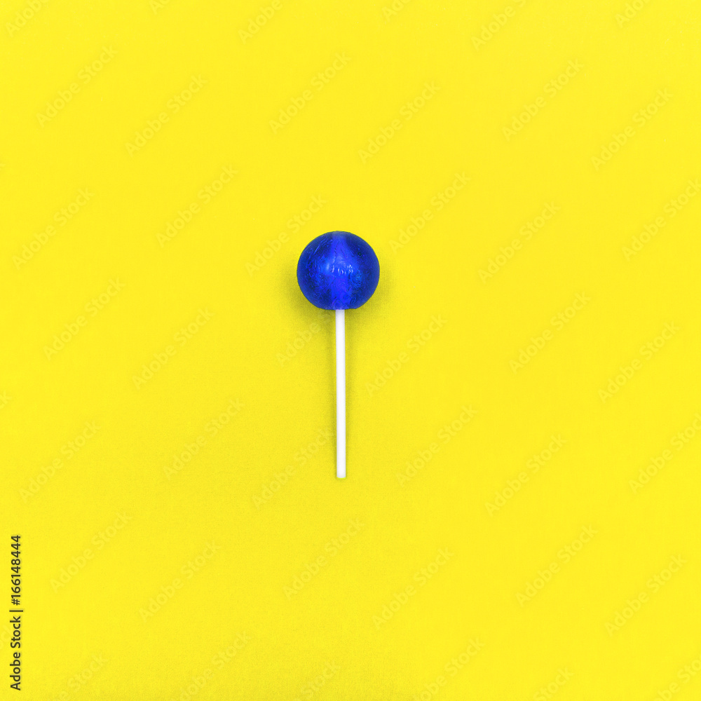 Lollipop Flat lay Minimal concept Blue round lollipop is lying on a yellow background Trendy bright photo in modern pop art style Top view