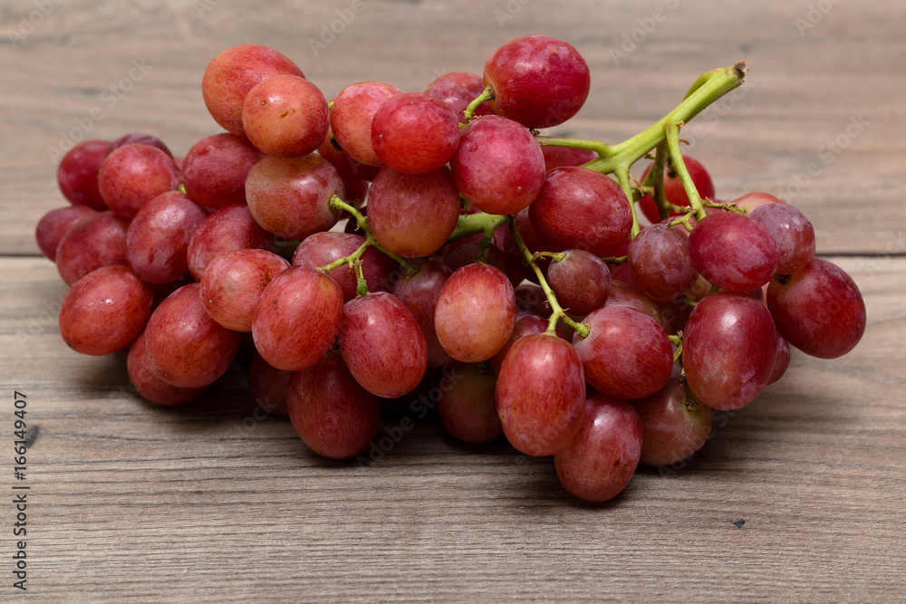 Cluster of grapes on top of a wooden table Cluster of grapes on top of a wooden table