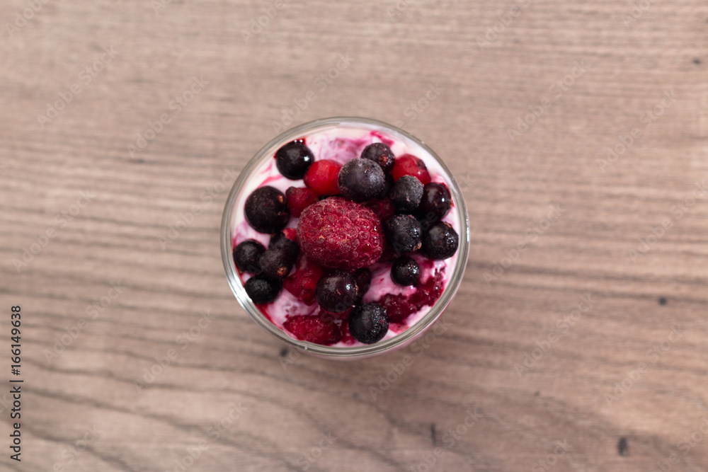Raspberries, blueberries, blackberries mixed with natural yogurt inside a small glass on a wooden table Raspberries, blueberries, blackberries mixed with natural yogurt inside a small glass on a wooden table