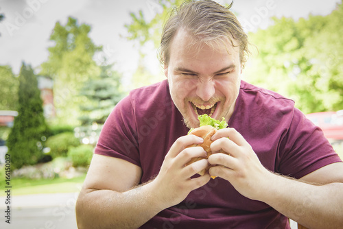 Obese fat man devouring a burger