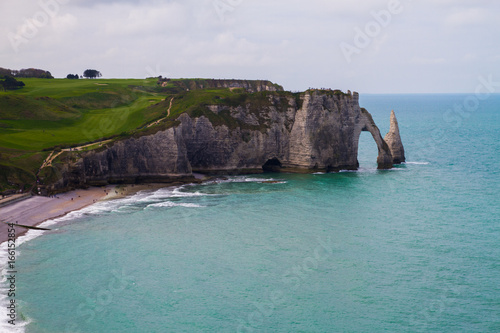 Etretat chalk cliffs, including three natural arches and a pointed formation called L'Aiguille or the Needle. Seine-Maritime department, Normandie, in north-western France. April 16th, 2017