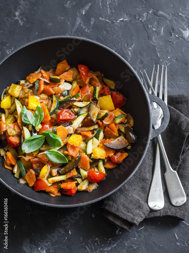 Photos Quick ratatouille in a cast iron skillet on a dark background, top view