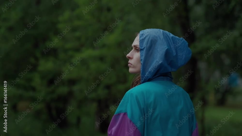Back View - Teenager Walks in Rainy Weather, in a Bright Colored Raincoat and Rubber Boots Blue Back View - Teenager Walks in Rainy Weather, in a Bright Colored Raincoat and Rubber Boots Blue