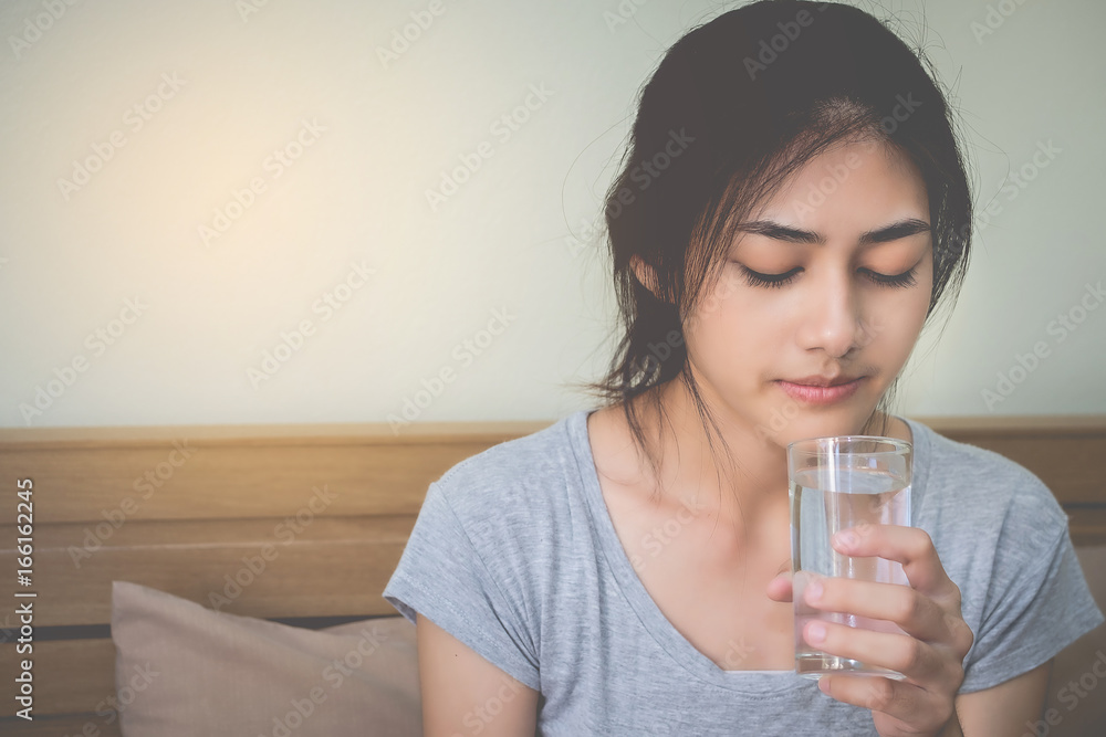 The woman is holding a glass of water with water to drink after waking up in the morning. The woman is holding a glass of water with water to drink after waking up in the morning.