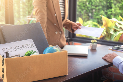 Close up of the hand employer filing final remuneration to resignation employee packing up all his personal belongings and files into a brown cardboard box, resign concept