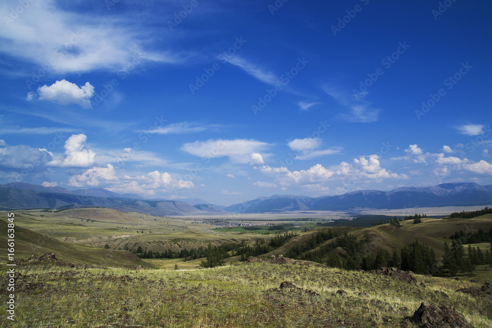 Cloud over the mountain range. Blue sky and green grass in a valley