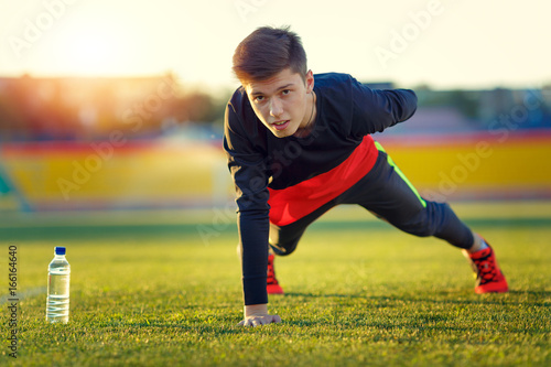 Young athlete doing an exercise in training on a green football field