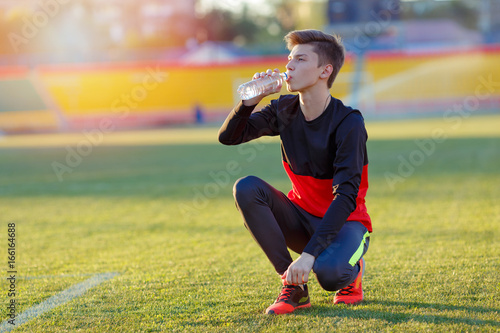 Athlete drinks water at the stadium on a hot sunny day