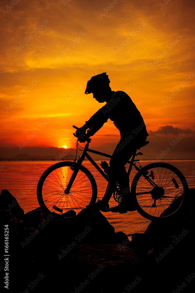 Obraz premium Healthy lifestyle. Silhouette of bicyclist riding the bike at seaside. Outdoors.