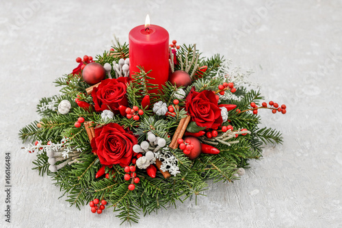 Christmas decoration with candle, red roses, fir, brunia and cinnamon sticks. photo