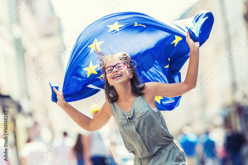 EU Flag. Cute happy girl with the flag of the European Union. Young teenage girl waving with the European Union flag in the city.