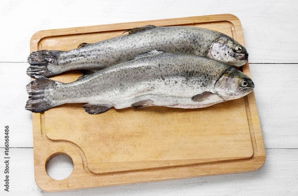 Two rainbow trouts on rustic wooden table.